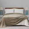 A green velvety blanket draped over a bed with white pillows and blue lamps on either side.