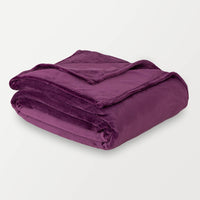 A folded plum-colored velvet blanket displayed on a white surface.