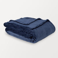 A folded dark blue velvet blanket displayed on a white surface.