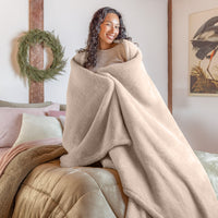 A woman wrapped in a beige extra fluffy blanket.