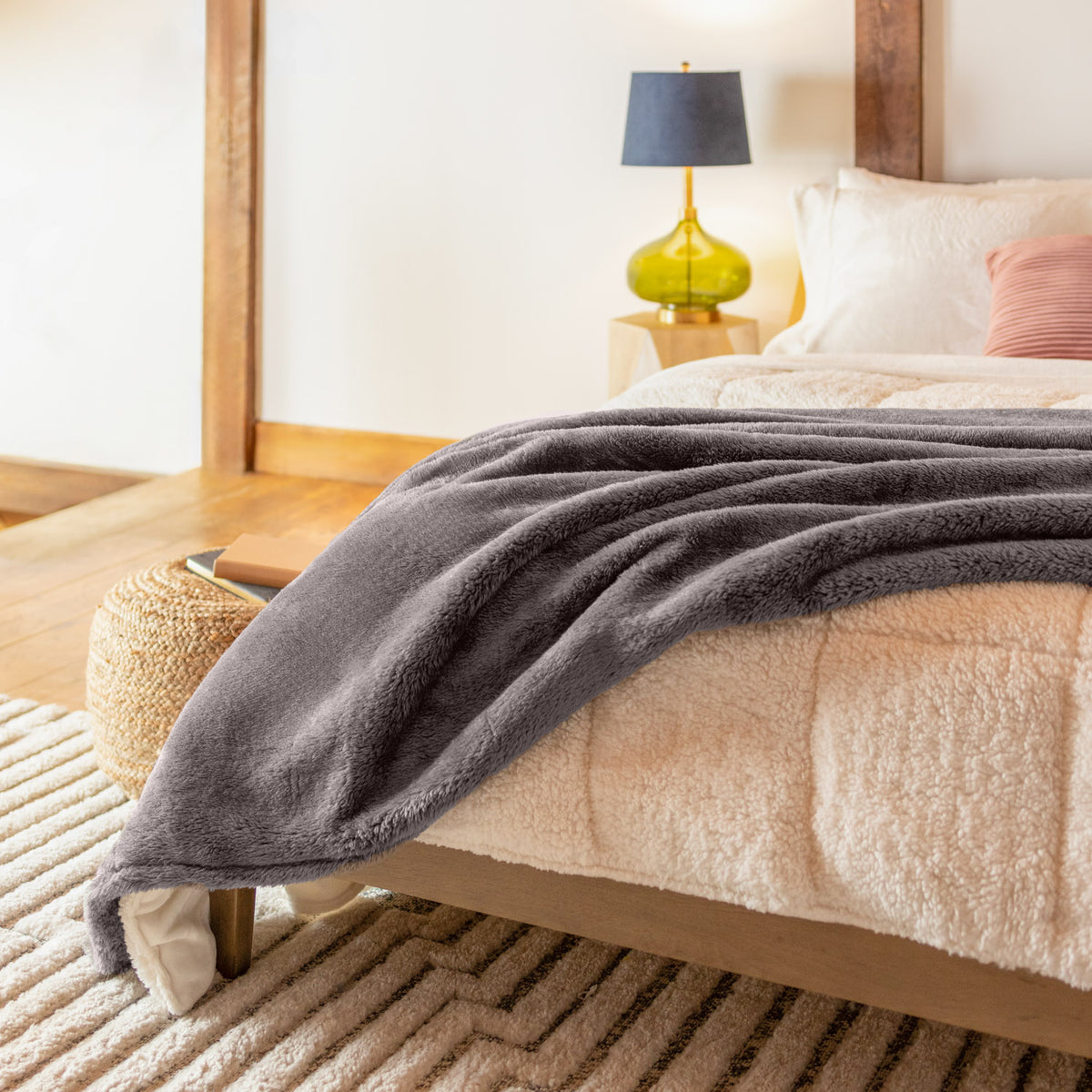 Bedroom setting of a cozy bed and a grey fluffy blanket.