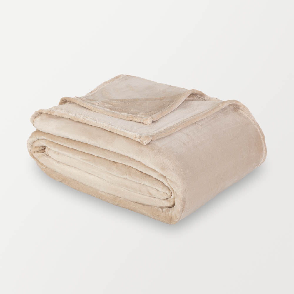 Beige velvety plush family blanket folded neatly on a white surface.