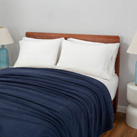 Polartec Softec Microfleece blanket in navy, draped elegantly over a white bed with blue lamps on both sides.