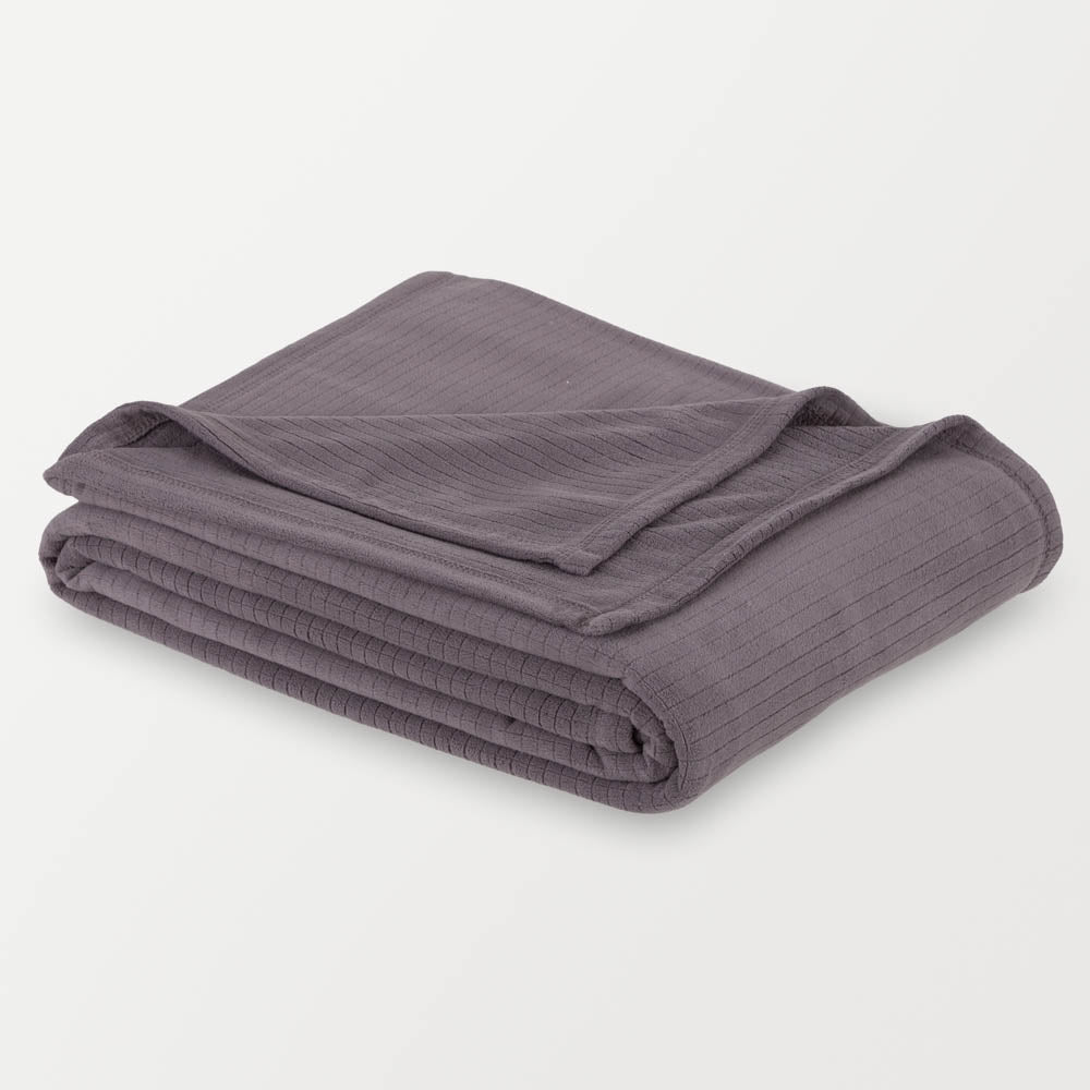 Folded gray Polartec blanket on a white surface, showcasing its compact and soft design.