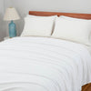 Bright bedroom scene with a Polartec Softec Microfleece blanket in white spread neatly over a bed.