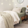 A Retro Comfort Plush Blanket draped over a stylized bed, with string lights and soft lighting in the background.