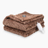 A heathered brown heated Faux Fur Throw folded neatly on a white surface.