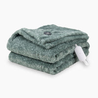 A heathered green heated Faux Fur Throw folded neatly on a white surface.