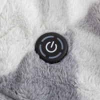 A close up of a grey fluffy heated throw with the power button in the center.