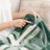 A close up of a person pressing the power button on a Faux fur Heated Throw using their pointer finger.