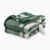 A green plaid heated Faux Fur Throw folded neatly on a white surface.