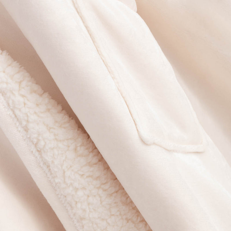 Detailed view of the soft cream-colored interior of the heated wearable throw.