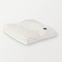 Folded cream heated wearable throw with visible power button.