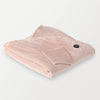 Folded soft pink heated wearable throw with the power button visible on the surface.