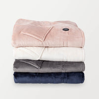 Four stacked heated wearable throws in pink, navy, cream, and gray.