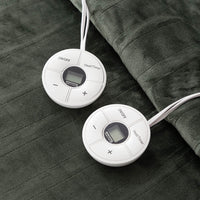 Two round controllers resting on a green heated blanket.