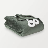 A folded green heated blanket with two round controllers placed on it.