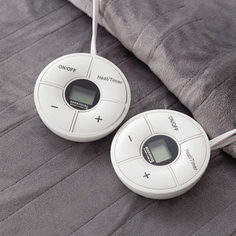 Close-up of two round controllers resting on a gray heated blanket.