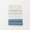 A stack of 6 pillowcases in cream, white, and blue folded neatly on a white surface.