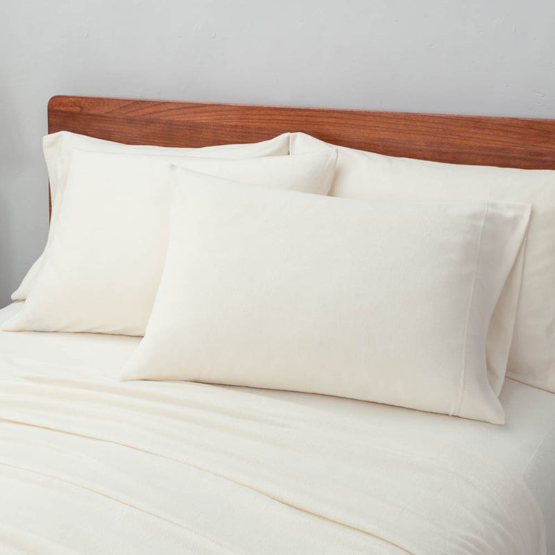 Warm ivory pillowcases displayed on a bed.