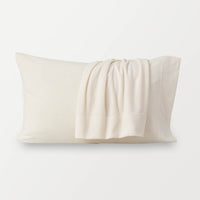 Warm ivory pillowcases displayed on a white surface. 