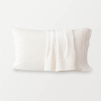 Cream pillowcases displayed ona w hite surface.