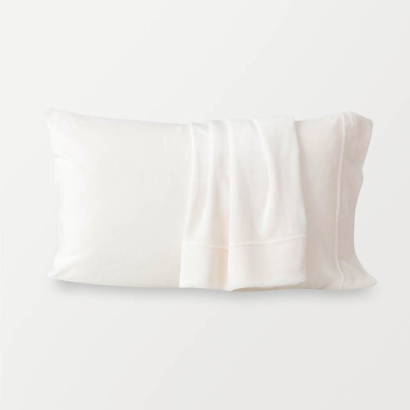 Cream pillowcases displayed ona w hite surface.