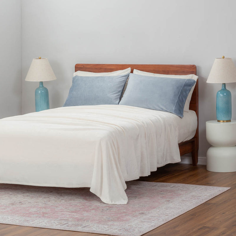 Blue pillowcases dressed on pillows displayed on a bed in a bedroom setting.