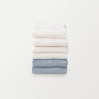 A stack of 6 pillowcases in white, cream, and blue folded neatly on a white surface.