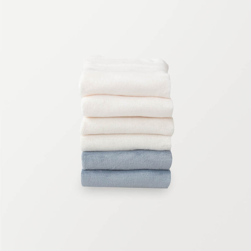 A stack of 6 pillowcases in white, cream, and blue folded neatly on a white surface.