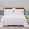 Bed with white bedding and wooden headboard in a room with two lamps on nightstands.