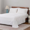 White bedspread on a wooden bed with a neutral background