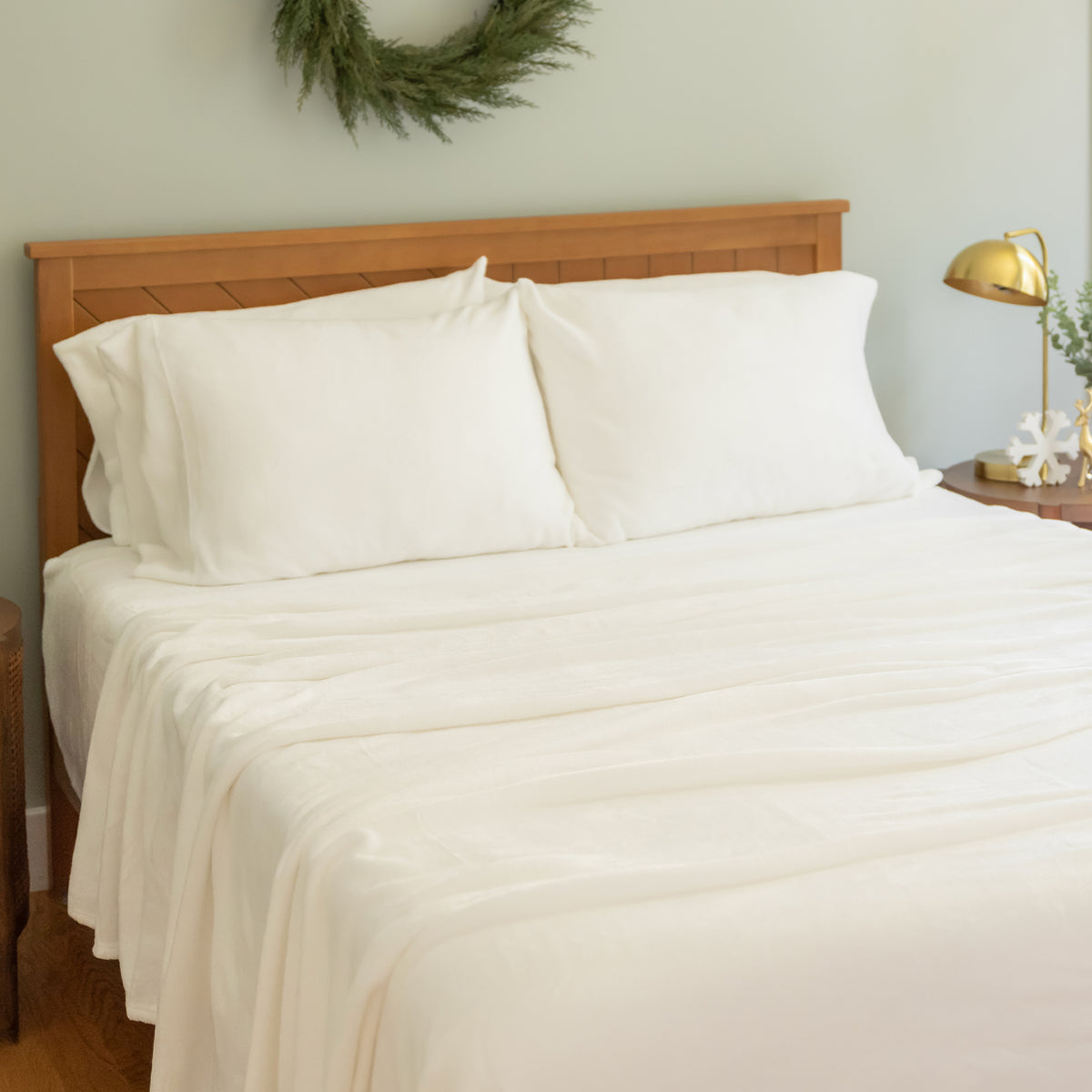 Bed with white bedding and wooden headboard in a room setting.