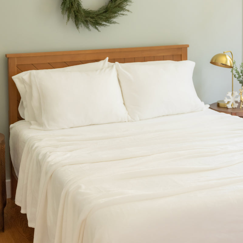 Bed with white bedding and wooden headboard in a room setting.