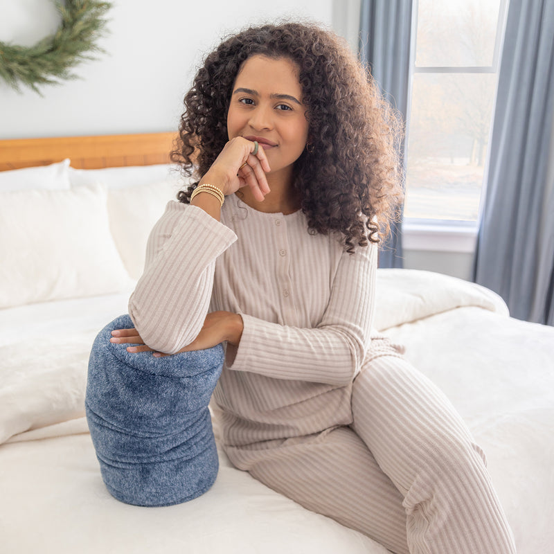 Woman sitting on a bed holding a blue pillow