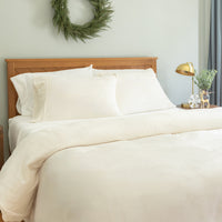 Neatly made bed with white bedding in a bedroom setting.