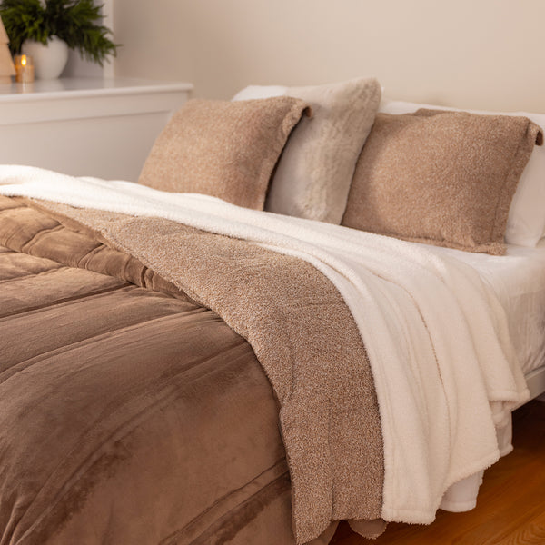 Bed with brown and beige bedding in a bedroom setting