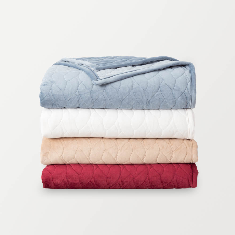 VelvetLoft® quilts stacked on top of each other in the four available colors—Polar Blue on top, followed by White, Linen, and Windsor Wine—displayed against a white background.