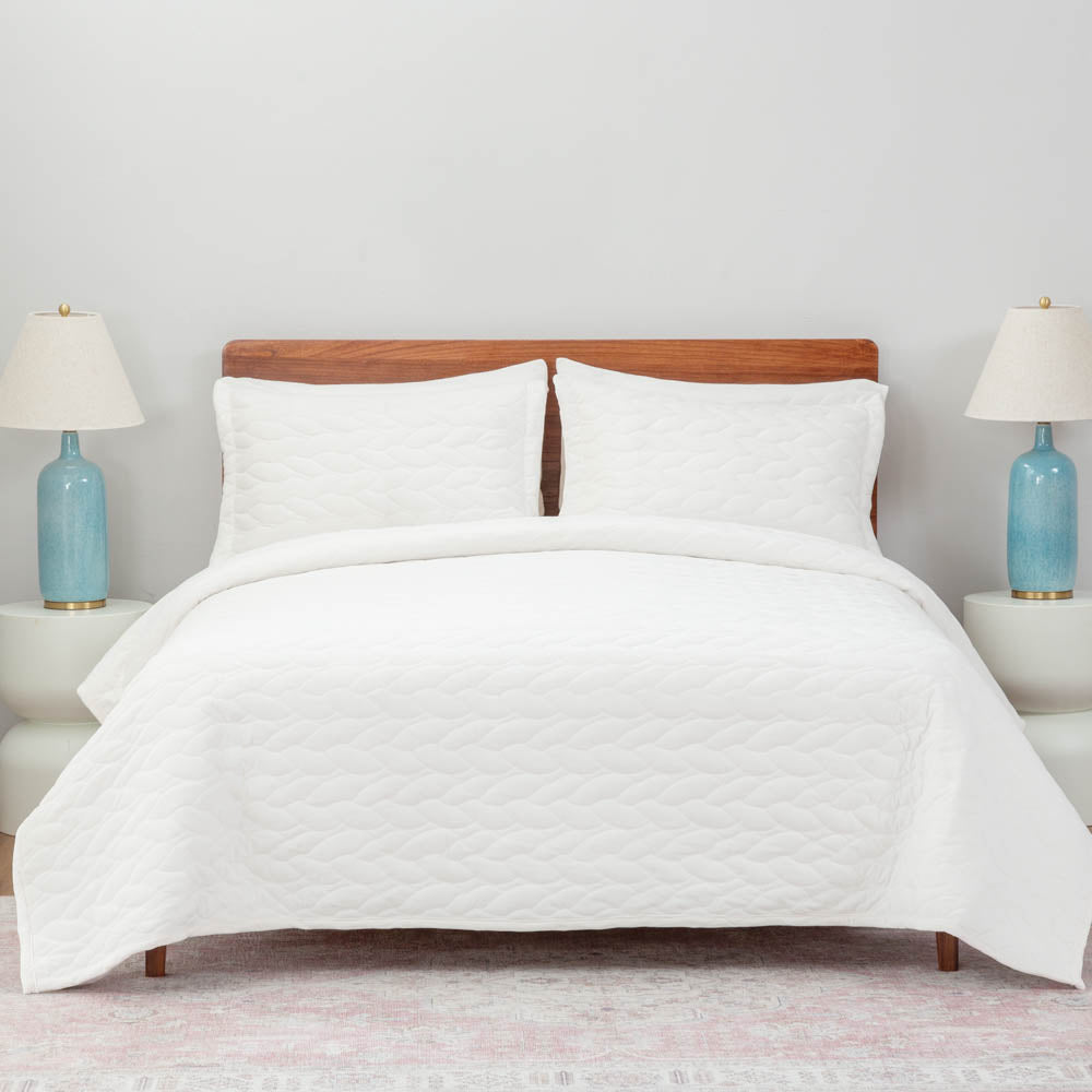 A bed made with the White VelvetLoft® Quilt Set, showcasing a clean and crisp bedding arrangement.