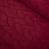 Close up of a red quilt set decorated on a bed.