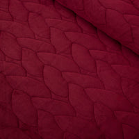 Close up of a red quilt set decorated on a bed.