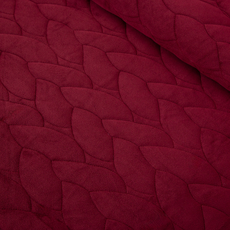 Close up of a red quilt set decorated on a bed.
