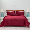 Red quilt set decorated on a bed in a neutral bedroom.
