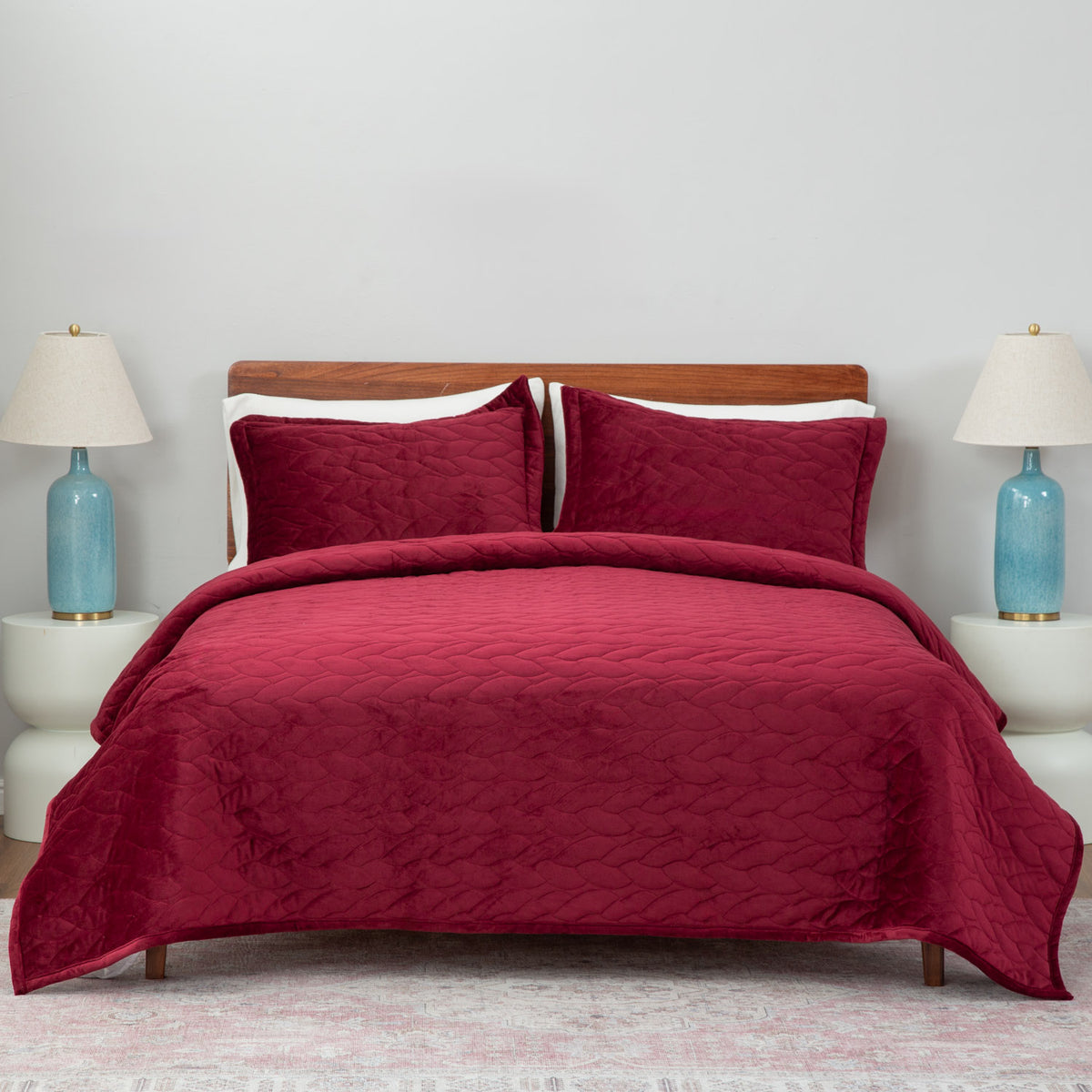 Red quilt set decorated on a bed in a neutral bedroom.