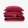 Stack of red quilted bedding on a white background