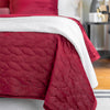 Red quilt with white lining draped over a chair in a room setting.