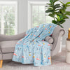 Blue Peanuts 75th Anniversary Throw draped neatly over a grey chair in a living space.