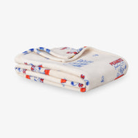 Printed Peanuts 75th Anniversary throw folded neatly on a white surface.