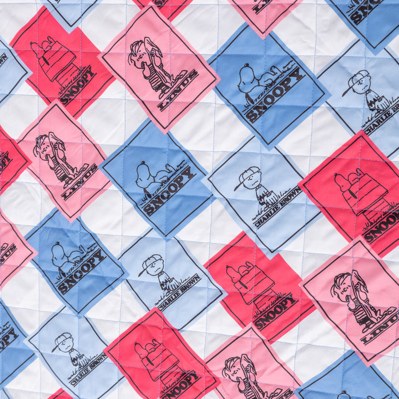 Close up of a blue and pink Peanuts 75th Anniversary packable outdoor blanket, showcasing the quilted texture.