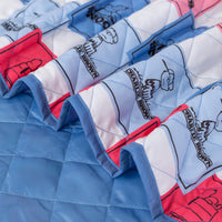 Close up of a blue and pink Peanuts 75th Anniversary packable outdoor blanket, showcasing the quilted texture.
